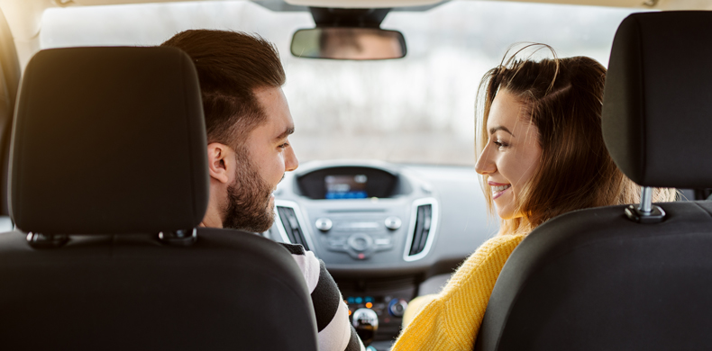Pärchen sitzt im Auto und lächelt